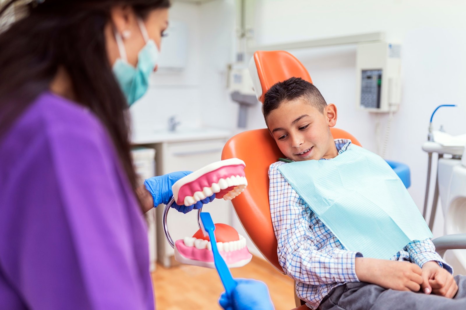 Doctor dentist teaching a child to brush teeth.